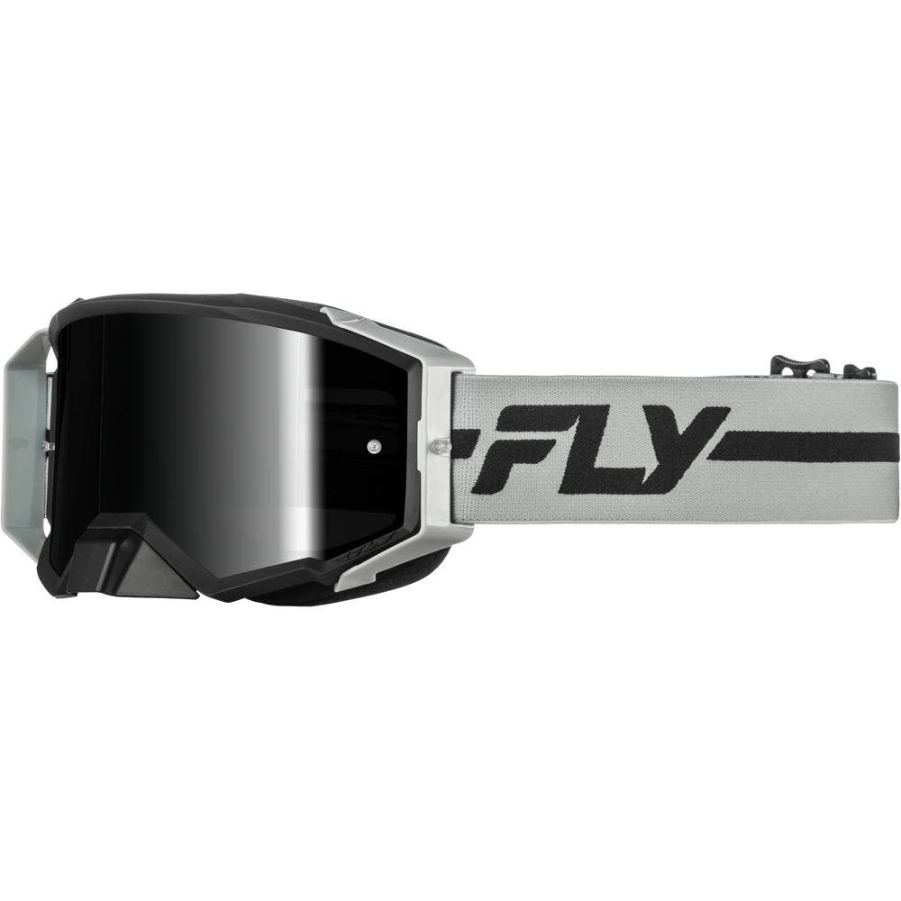A pair of motocross goggles with a black mirrored lens, a black and silver frame, and a light gray strap featuring a bold black 'FLY' logo.