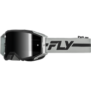 A pair of motocross goggles with a black mirrored lens, a black and silver frame, and a light gray strap featuring a bold black 'FLY' logo.