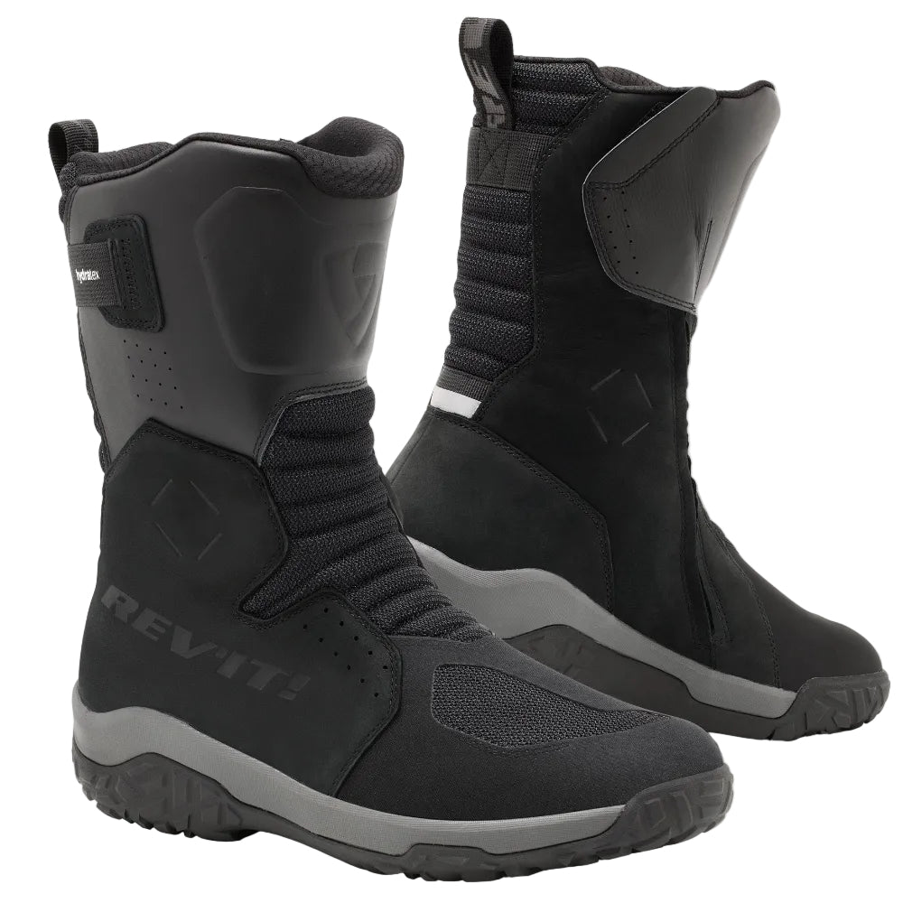 A pair of black REV'IT! mid-calf riding boots with gray accents, shown from the side and back on a light beige background.