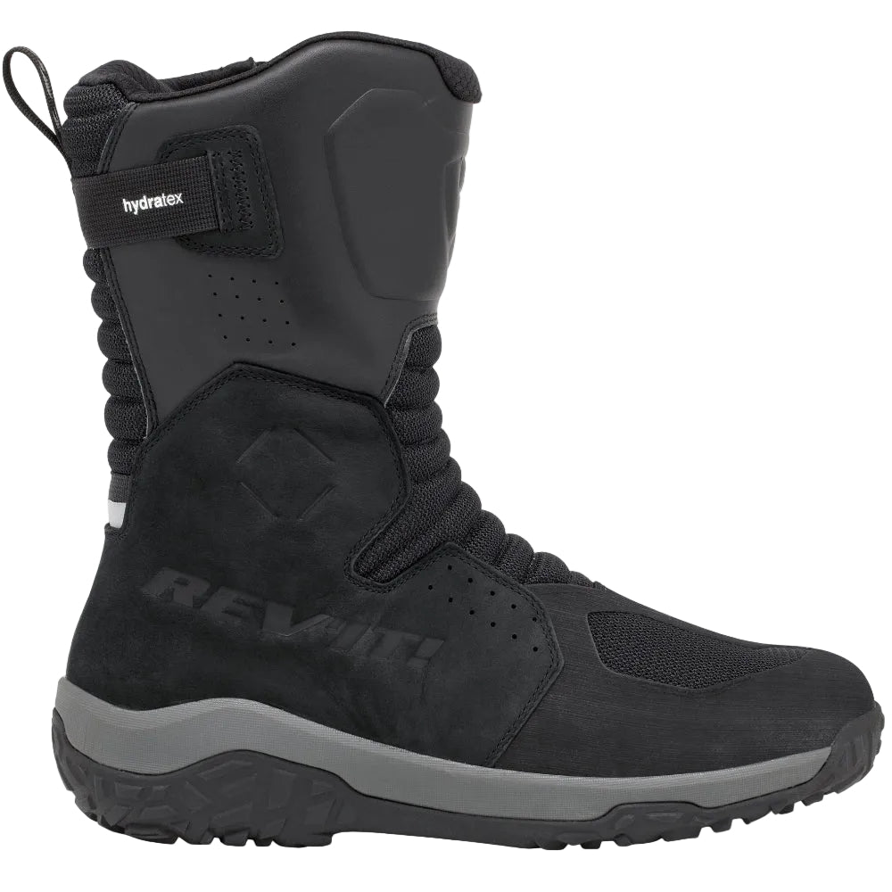 A black Rev'it! mid-height riding boot with a gray midsole, shown in a side profile against a light beige background.
