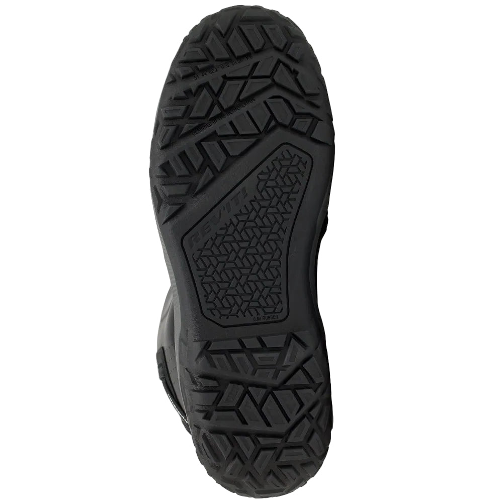 A close-up, top-down view of a black shoe sole with a textured, treaded pattern, set against a solid off-white background.