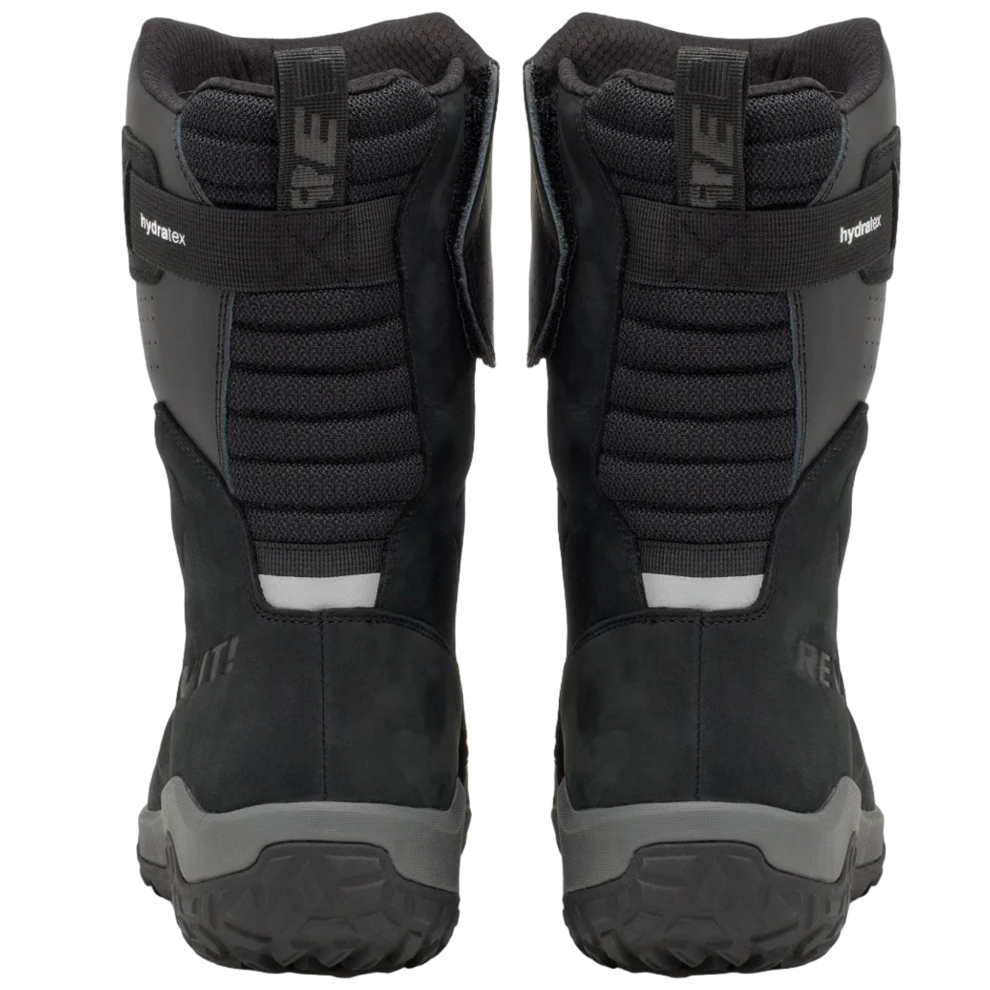 A pair of black and dark gray snowmobile boots shown from the back, featuring textured panels, a hook-and-loop strap closure, and rugged tread soles, set against a light off-white background.