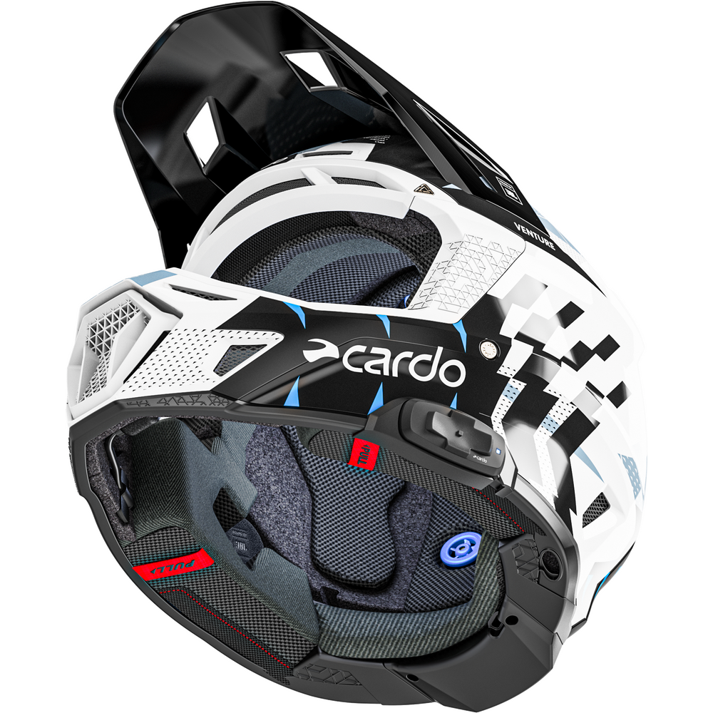 A close-up of a Cardo off-road motorcycle helmet, showing the interior padding, ventilation slots, and the black, white, and blue exterior graphics.