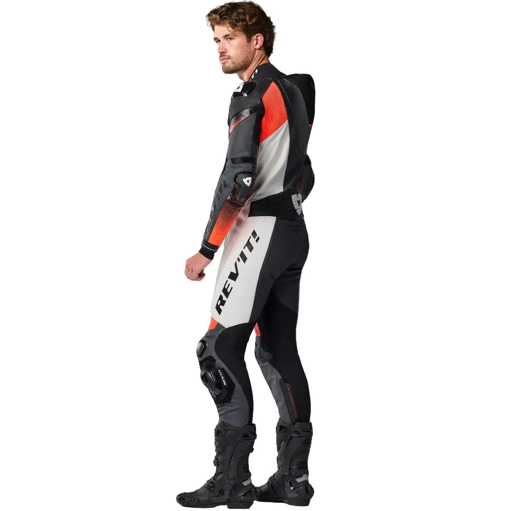 Person wearing a black, gray, and red motorcycle suit with 'Rev' branding on a white background