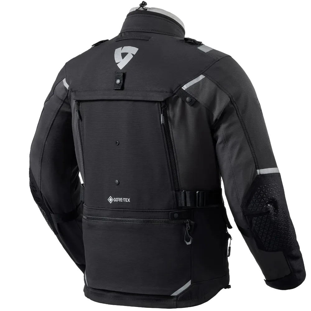 Black GORE-TEX motorcycle jacket shown from the back on a mannequin torso, featuring reflective silver-gray stripes and a GORE-TEX logo on the lower back.