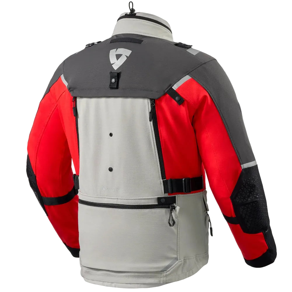 A red, gray, and black motorcycle jacket shown from the back on a mannequin, featuring a large central zippered pocket and a triangular logo on the upper back.