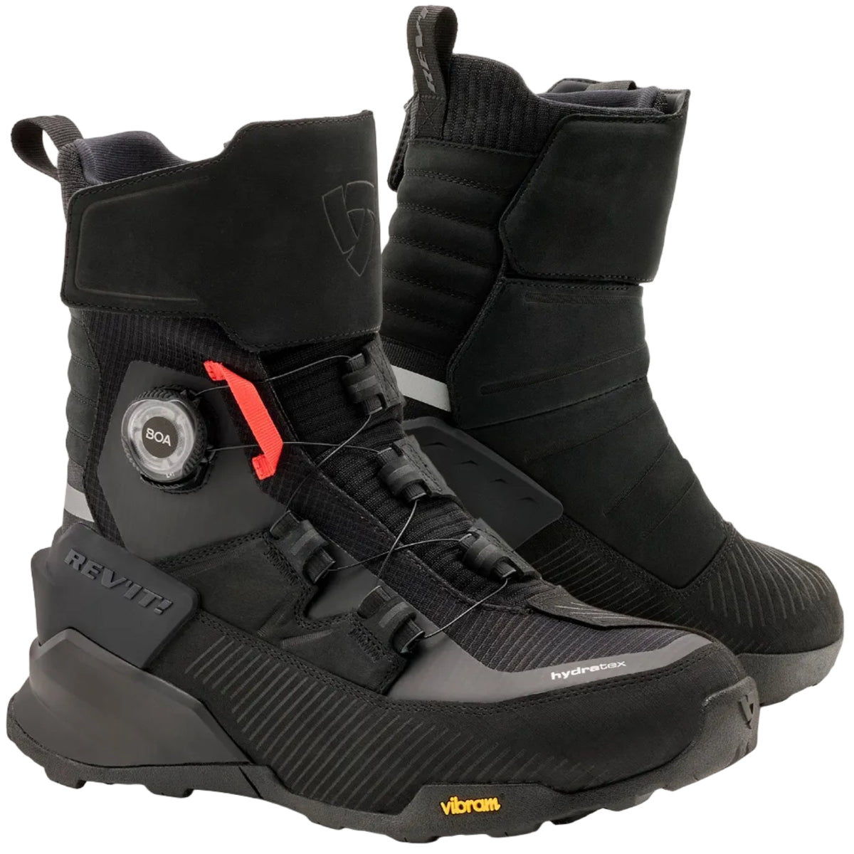 A pair of black mid-calf riding boots with a dial closure system and a small red accent, displayed on a light beige background. The brand 'Vibram' is visible on the toe area.