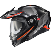 A black full-face motorcycle helmet with a clear visor, featuring orange accent stripes and a gray graphic pattern on the shell, shown against a plain white background.