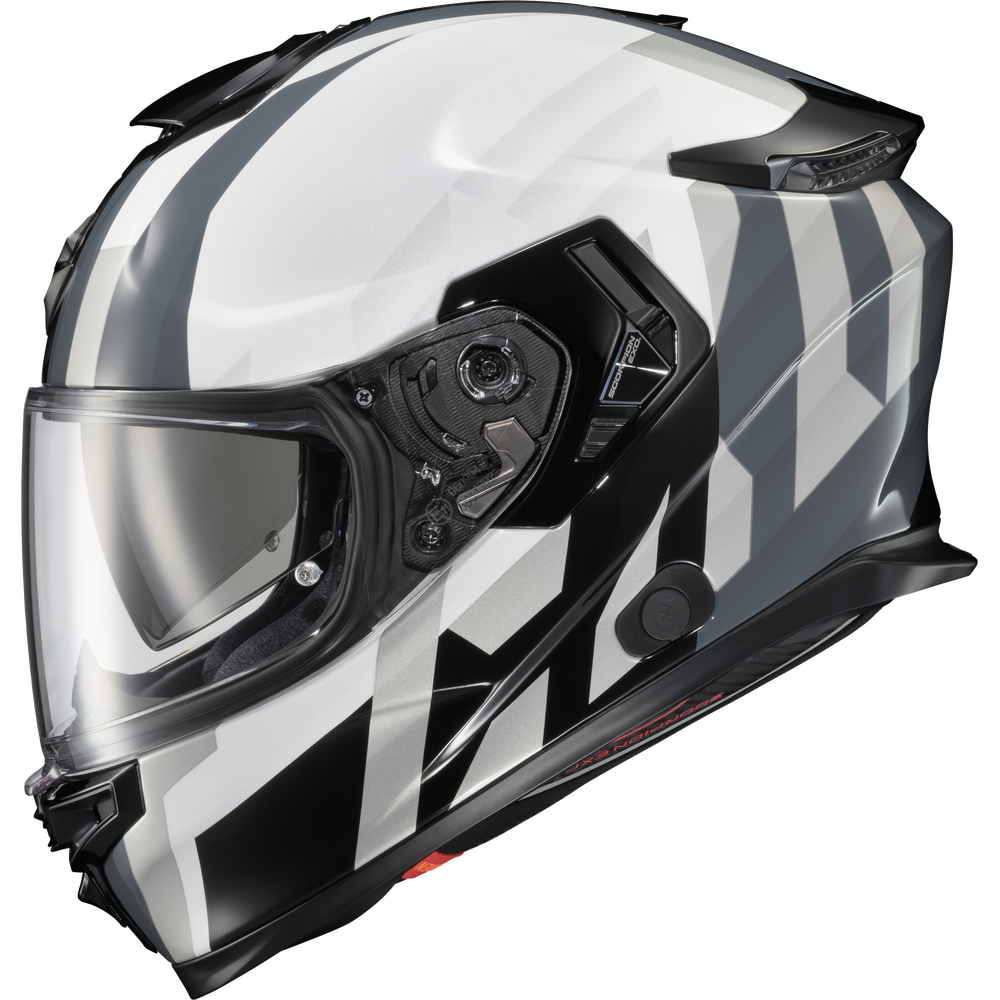 A full-face motorcycle helmet with a glossy white, black, and gray geometric pattern, featuring a clear visor and black chin bar, shown against a plain white background.
