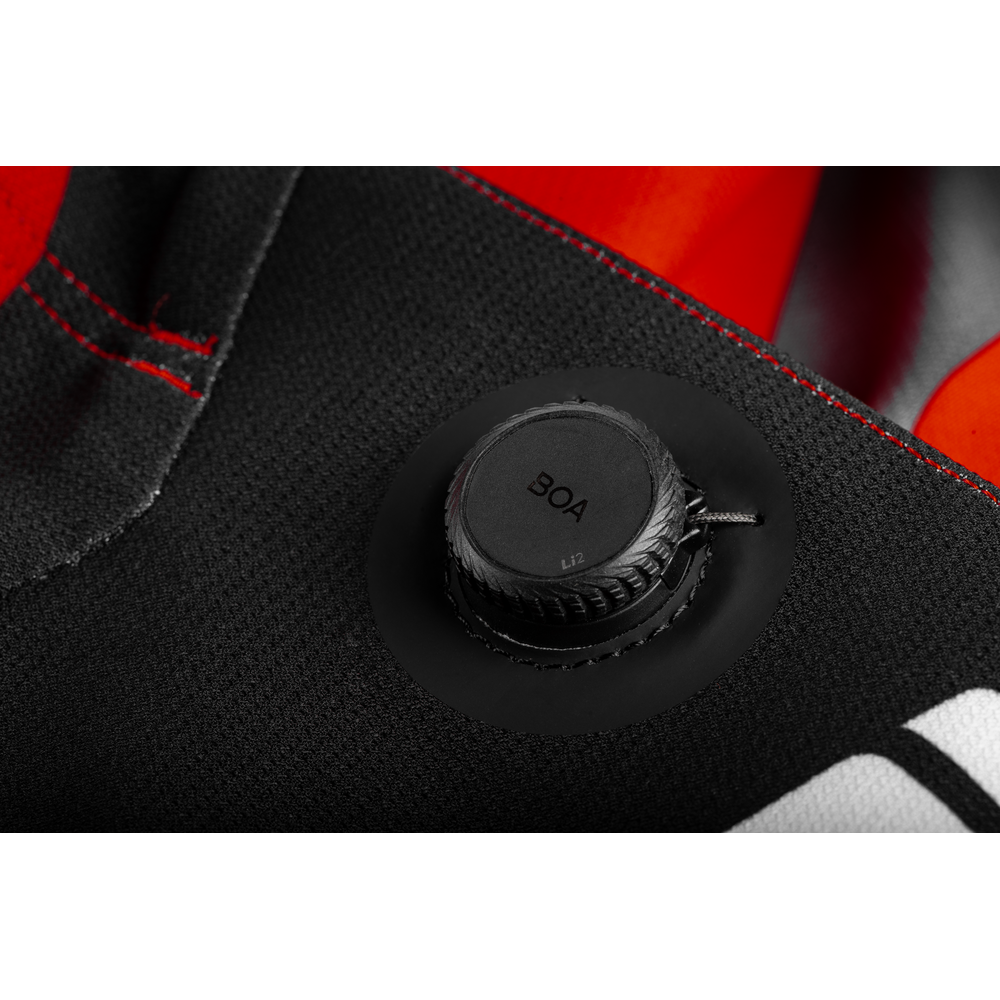 Close-up of a black circular dial with the text 'BOA' on a black textured fabric surface with red and orange accents.
