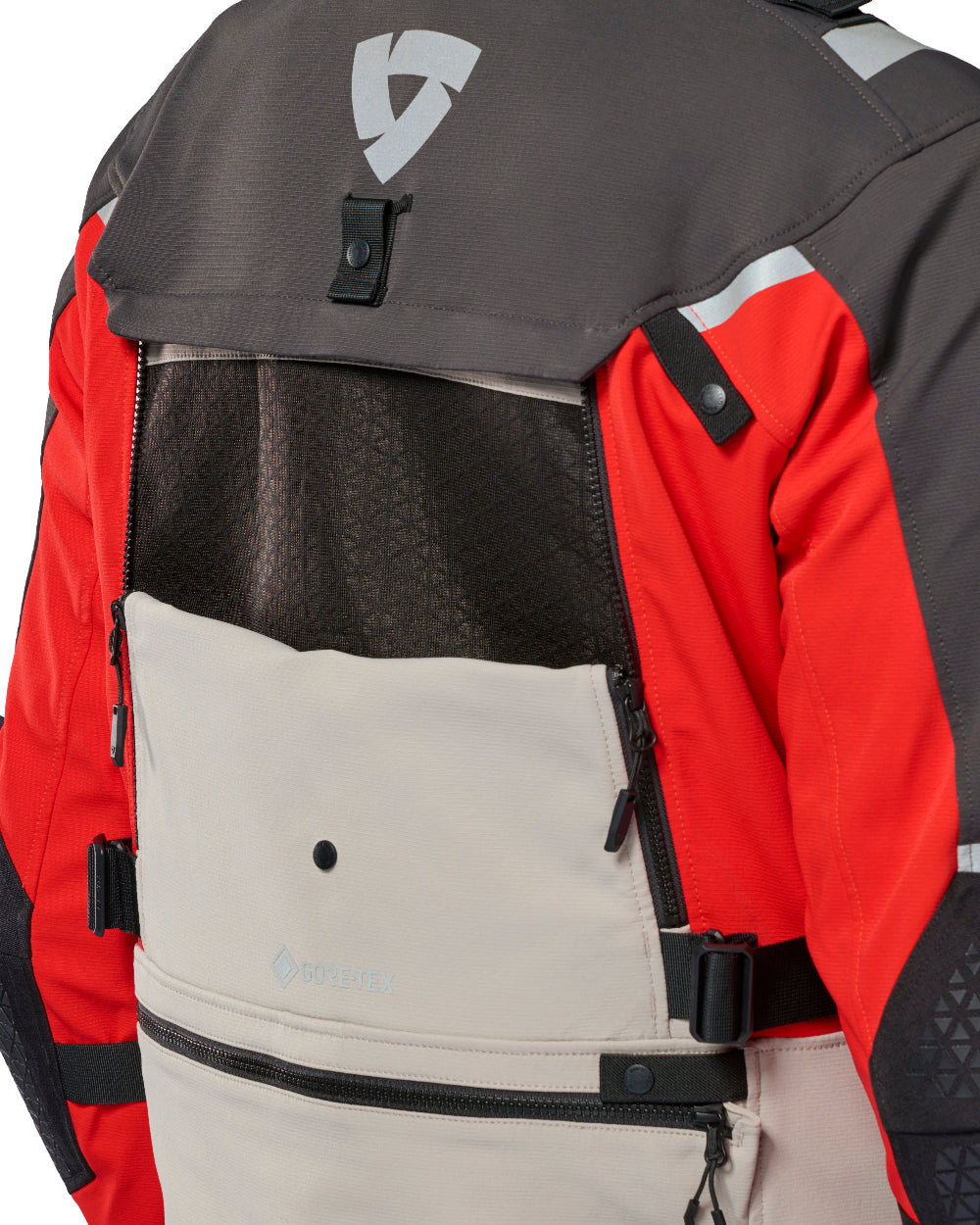 Close-up of the back of a technical outdoor jacket with a dark gray upper panel, bright red sleeves, a beige lower pocket, black mesh ventilation, and reflective silver details.