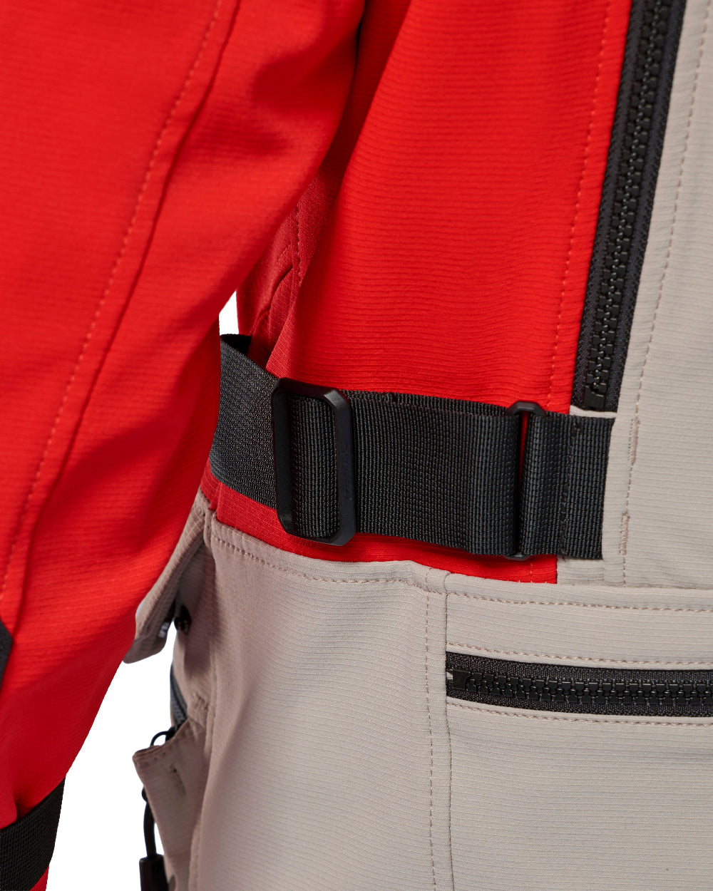 Close-up of a red and light gray technical jacket with a black adjustable waist belt and zipper details.