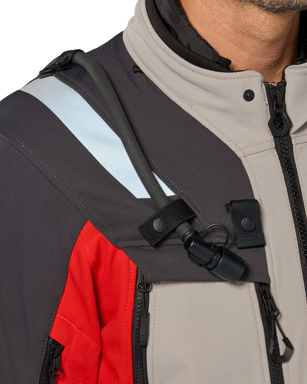 Close-up of a person wearing a technical jacket with a hydration tube routed across the chest under a black chest strap.