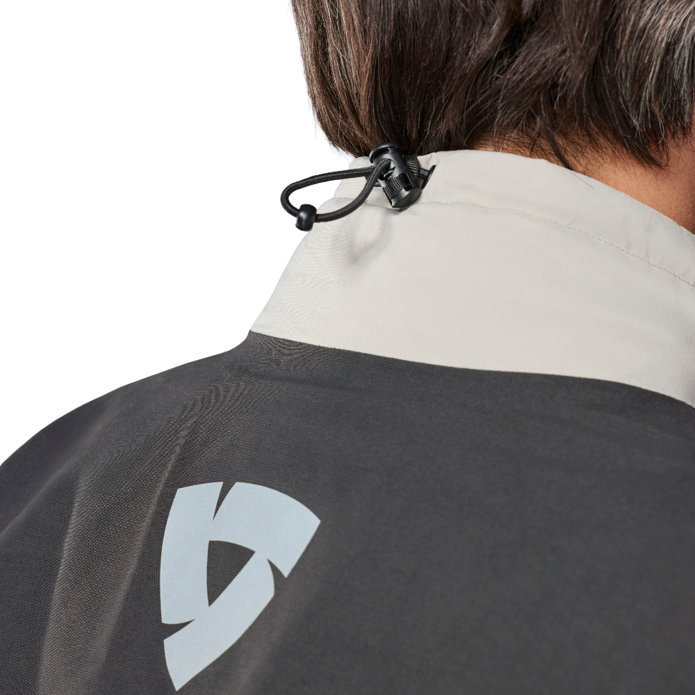 Close-up back view of a person wearing a dark gray and off-white jacket, showing the neck, hair, and a white geometric logo on the back.