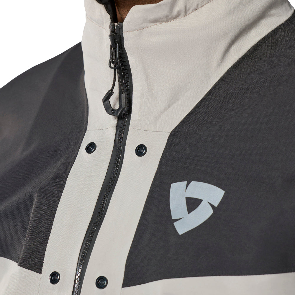 Close-up of a men's colorblock jacket featuring a light beige and dark gray color scheme, with a black front zipper and a light gray geometric logo on the chest.