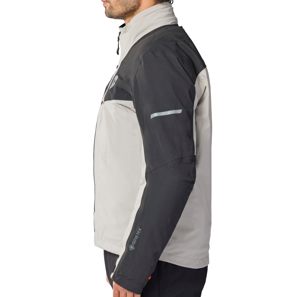 A man shown in profile wearing a color-blocked jacket with a light gray body, dark gray shoulders and upper chest, and dark sleeves, paired with dark pants, against a plain white background.