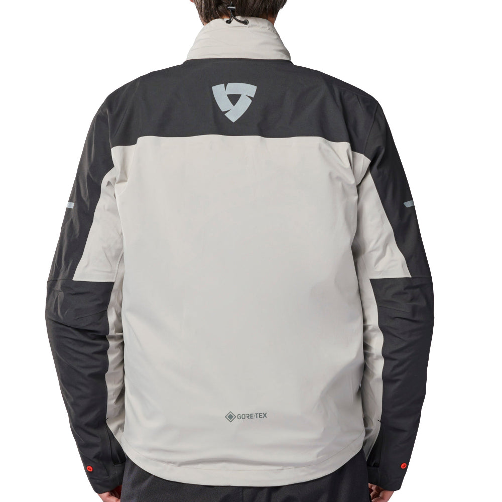 A man viewed from behind wearing a GORE-TEX jacket with a color-blocked design of light gray and black, paired with black pants, against a solid white background.