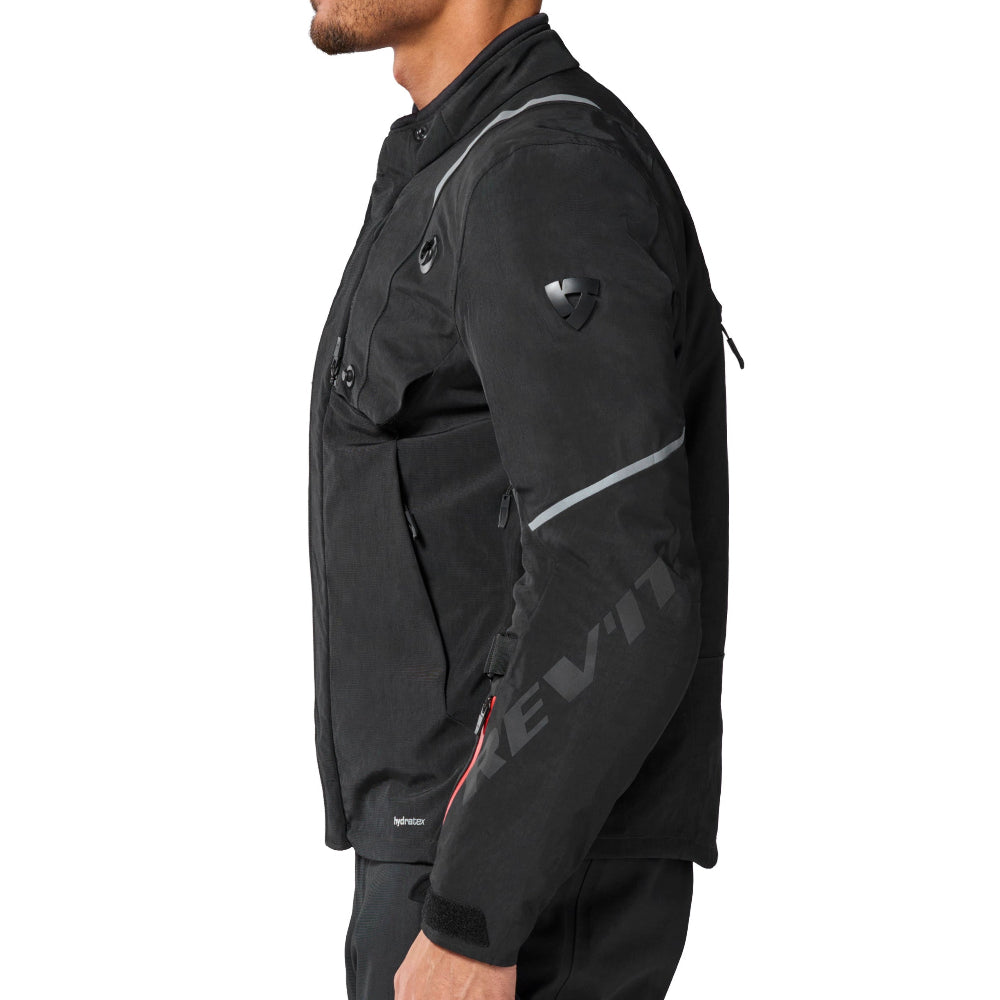 A man in profile wearing a black Levi's motorcycle jacket with reflective gray stripes and a gray logo, paired with black pants, against a solid white background.