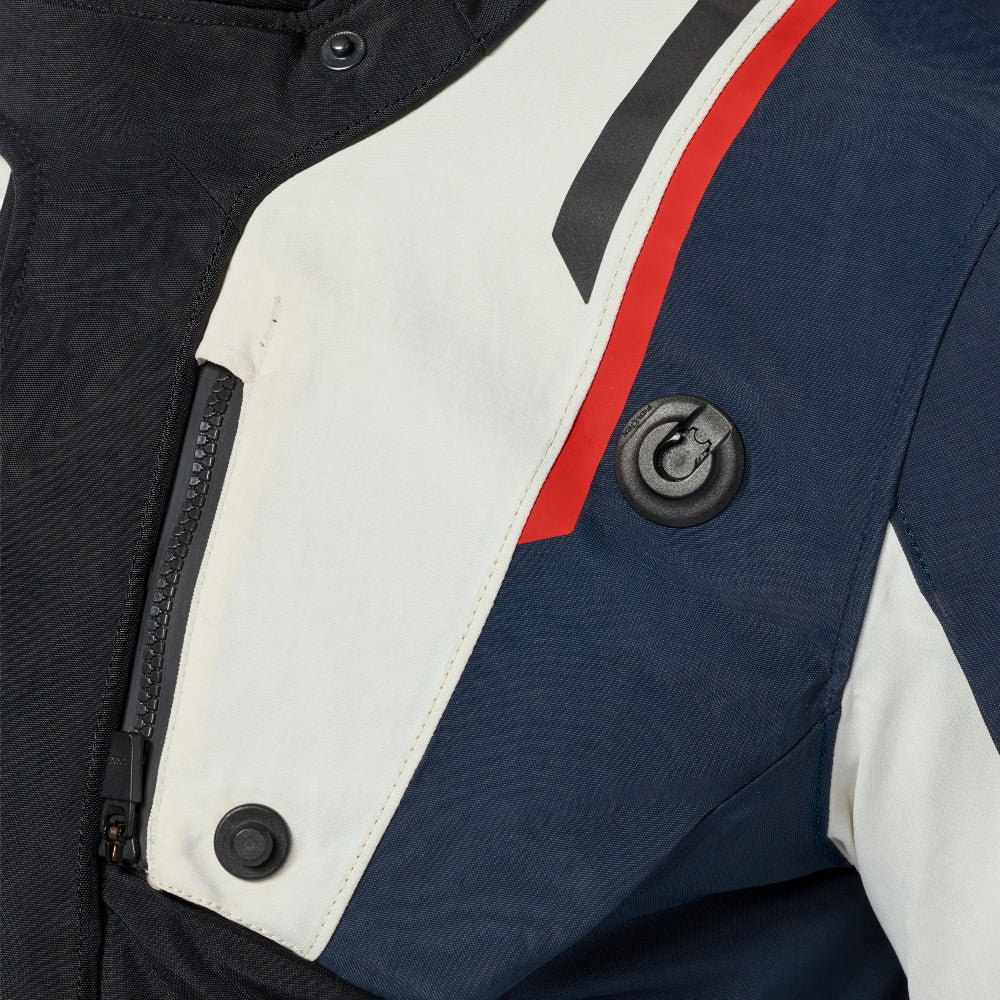Close-up of a motorcycle jacket showing the chest panel with color-blocked sections of navy blue, off-white, and black, accented by a red stripe.