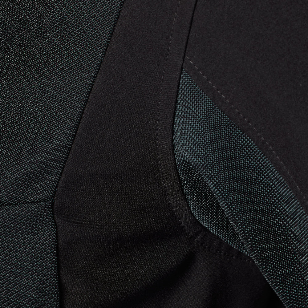 Close-up detail of a black athletic jacket showing different fabric textures and a curved seam.