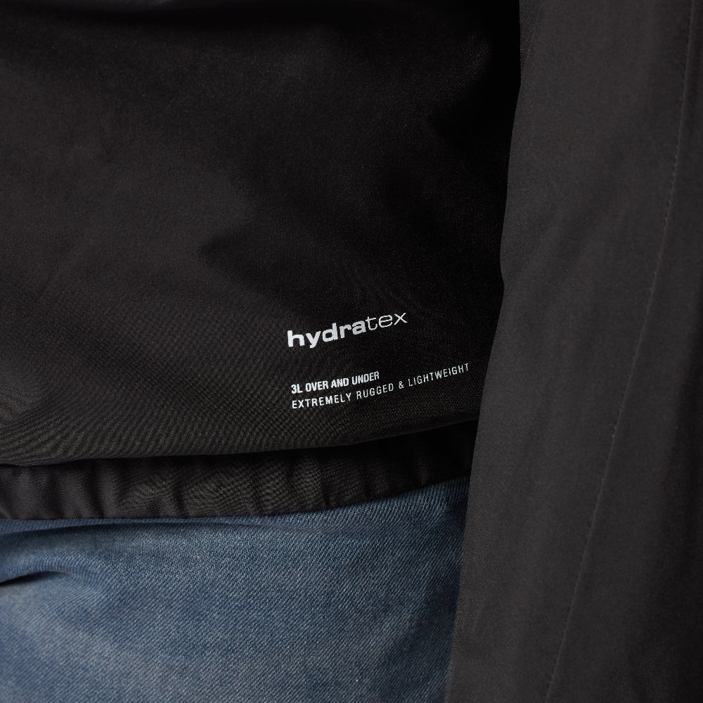 Close-up of a black jacket with 'hydratex' branding on a dark background