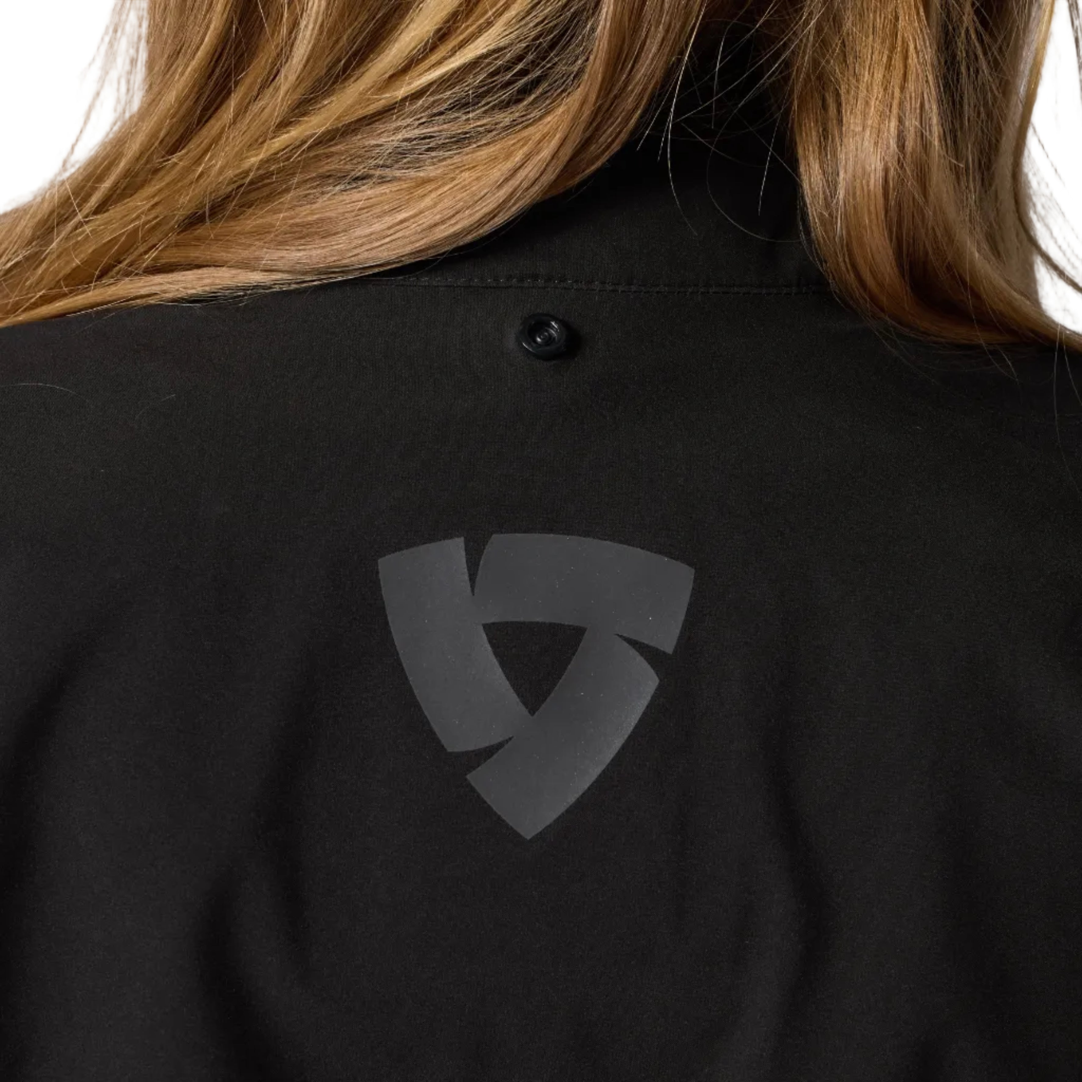 Black shirt with a logo on the chest, worn by a person with blonde hair.