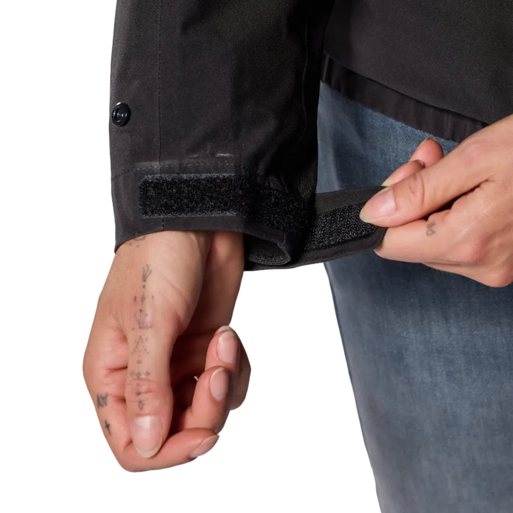Person adjusting a black jacket with a button on a light gray background