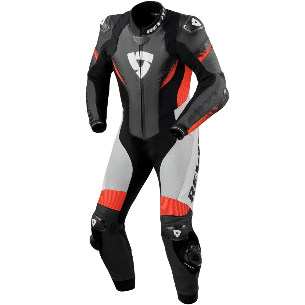 A full-body leather motorcycle racing suit by Dainese, featuring a color-blocked design of black, gray, white, and red-orange. The suit includes protective armor inserts on the shoulders, elbows, and knees, and the Dainese shield logo is prominently displayed on the chest and legs.