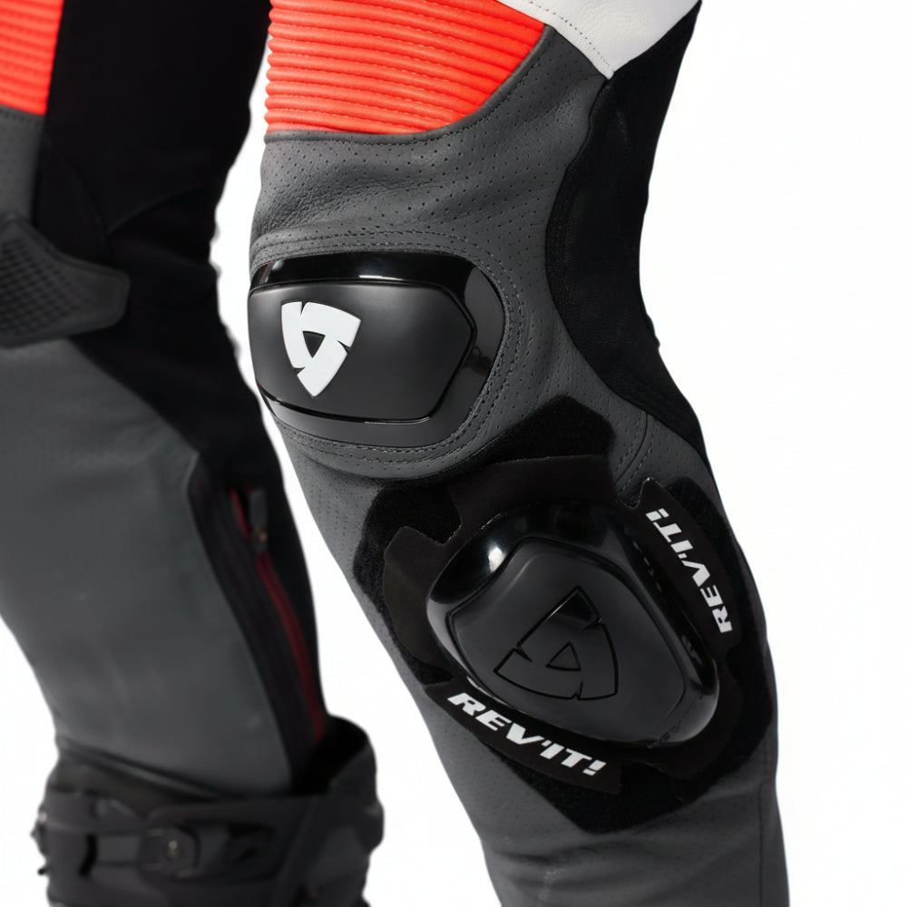Close-up of a black knee pad with 'REV'IT!' branding on a gray background