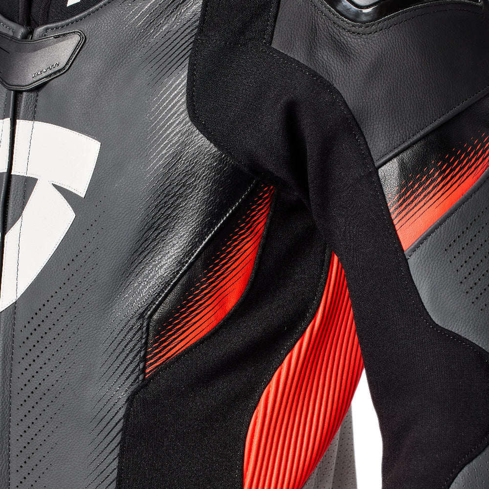 Close-up of a black leather motorcycle jacket with red and white graphic accents, showing the textured leather material and protective paneling.