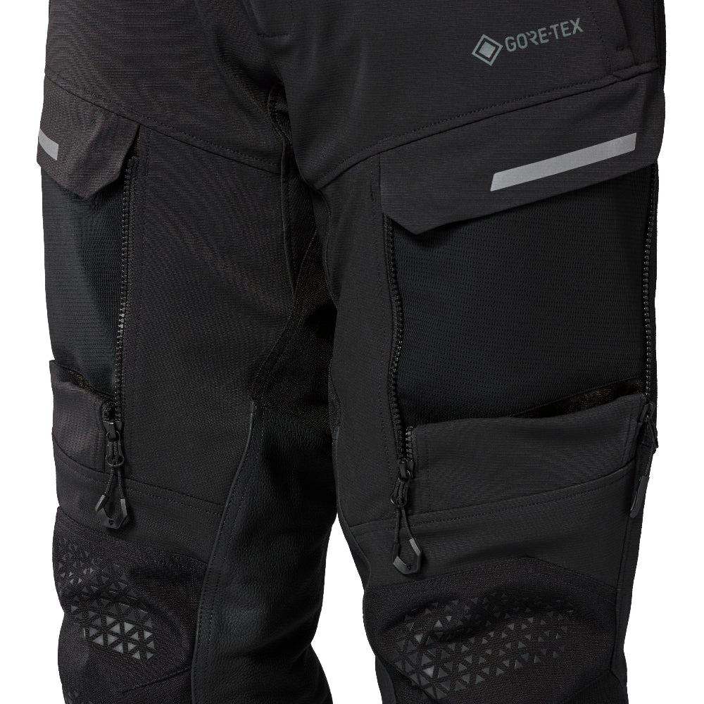 Black GORE-TEX motorcycle pants with multiple zippered venation panels, reflective stripe details, and textured knee protection, shown on a white background.