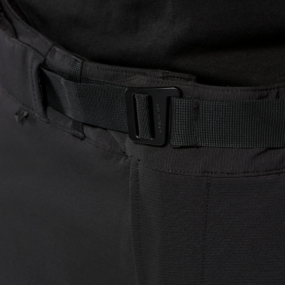 Close-up of a black tactical belt with a matte black metal quick-release buckle, worn over black pants.