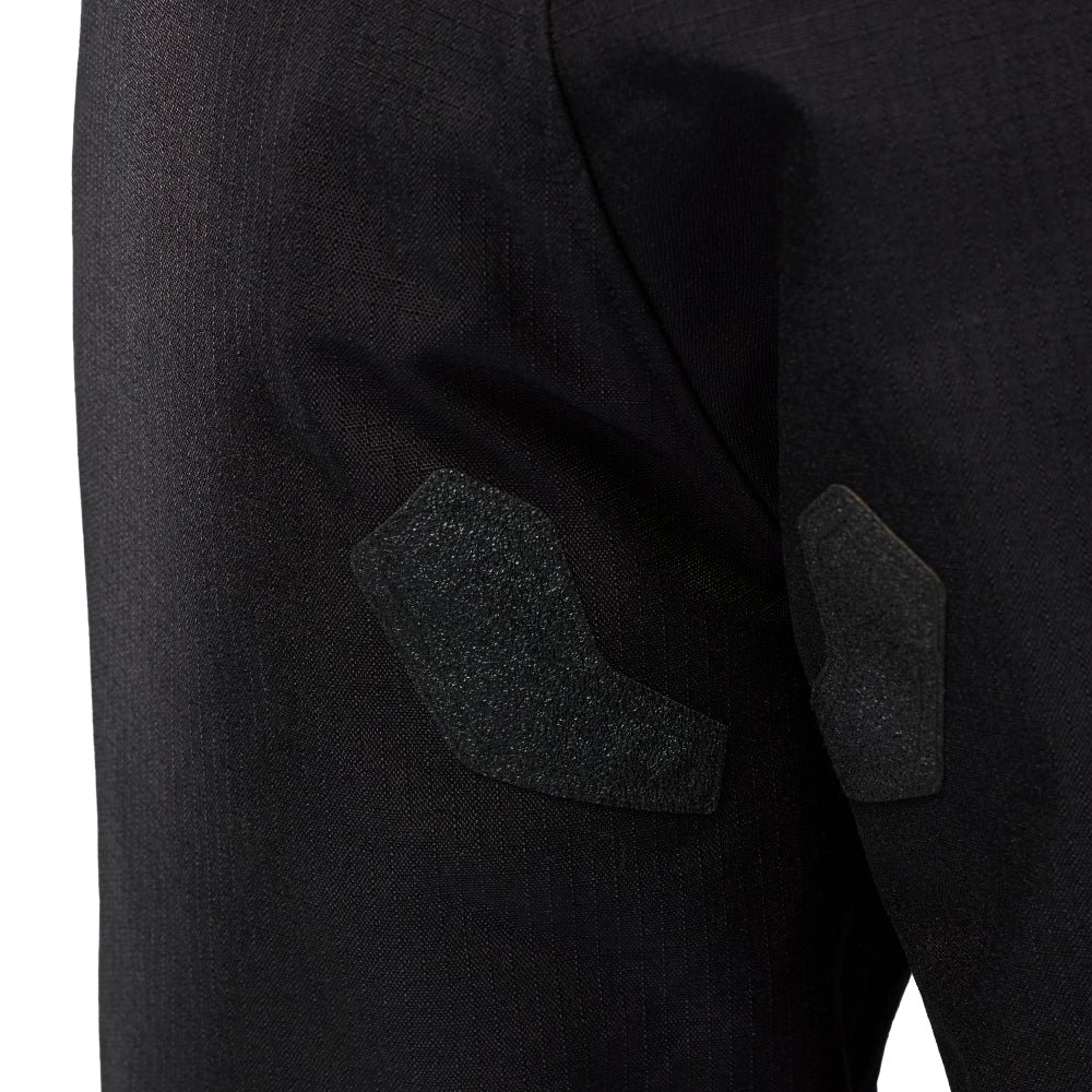 Close-up of black trousers showing textured black grip patches on the seat area, set against a plain white background.