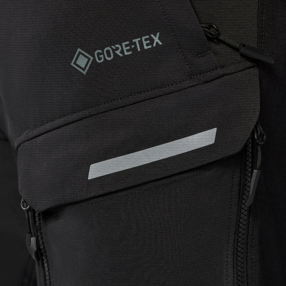 Close-up of a black Gore-Tex jacket pocket with a reflective silver stripe and the Gore-Tex logo embroidered in gray.