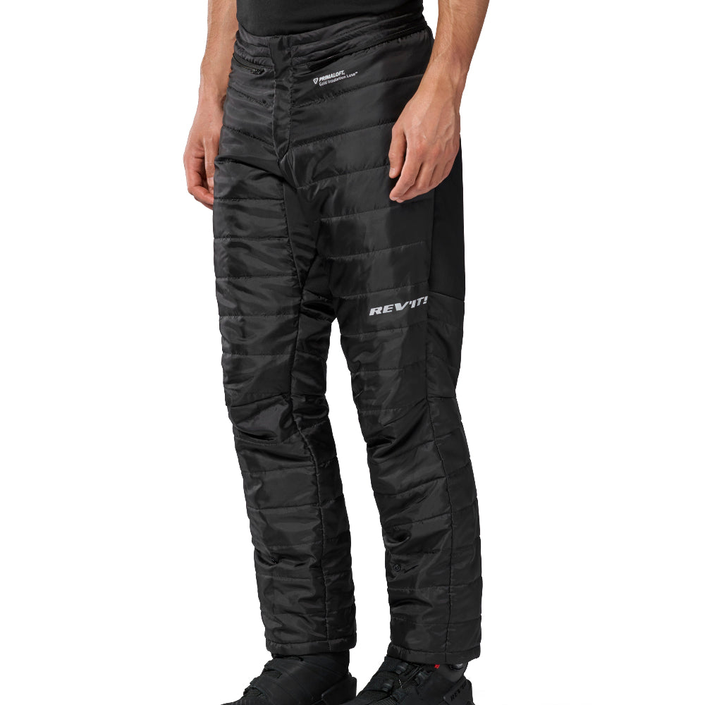 Black insulated motorcycle pants with quilted padding and white RE'IT branding on the left thigh, shown on a model from the waist down against a white background.