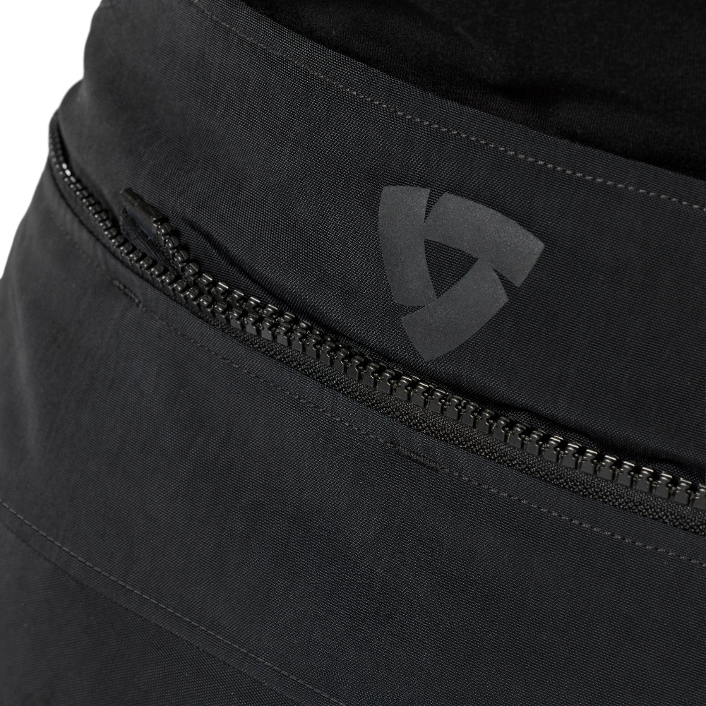 Close-up of a black jacket attachment zippers on dark gray or black fabric, featuring a tonal dark gray shield logo on the front.
