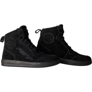 A pair of black high-top boots with a matte finish, featuring a circular logo on the side and a pull tab at the heel, shown against a plain white background.