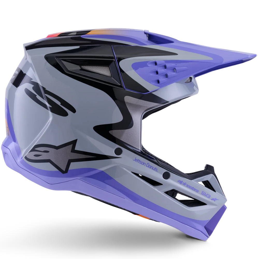 A motocross helmet in a metallic silver-gray and purple colorway with black graphic accents, featuring the Alpinestars logo on the side, shown against a plain white background.