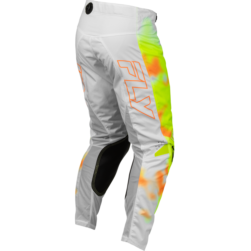 White motocross pants with a vibrant neon yellow, green, and orange tie-dye pattern on the right leg, featuring a large orange outlined 'FLY' logo on the side and black knee protection.