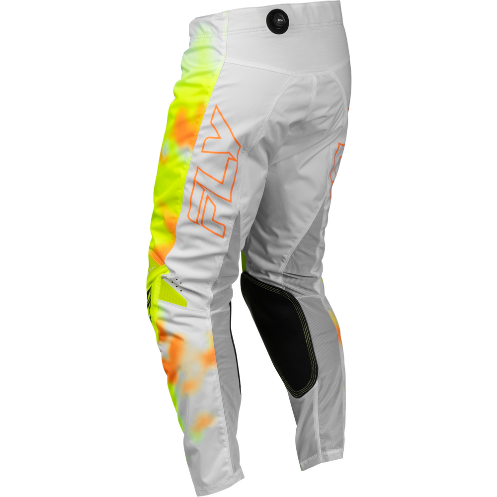 White motocross pants with a vibrant neon yellow, orange, and green graphic pattern down the left leg, featuring a large orange outlined 'FLY' logo on the side and black knee pads.