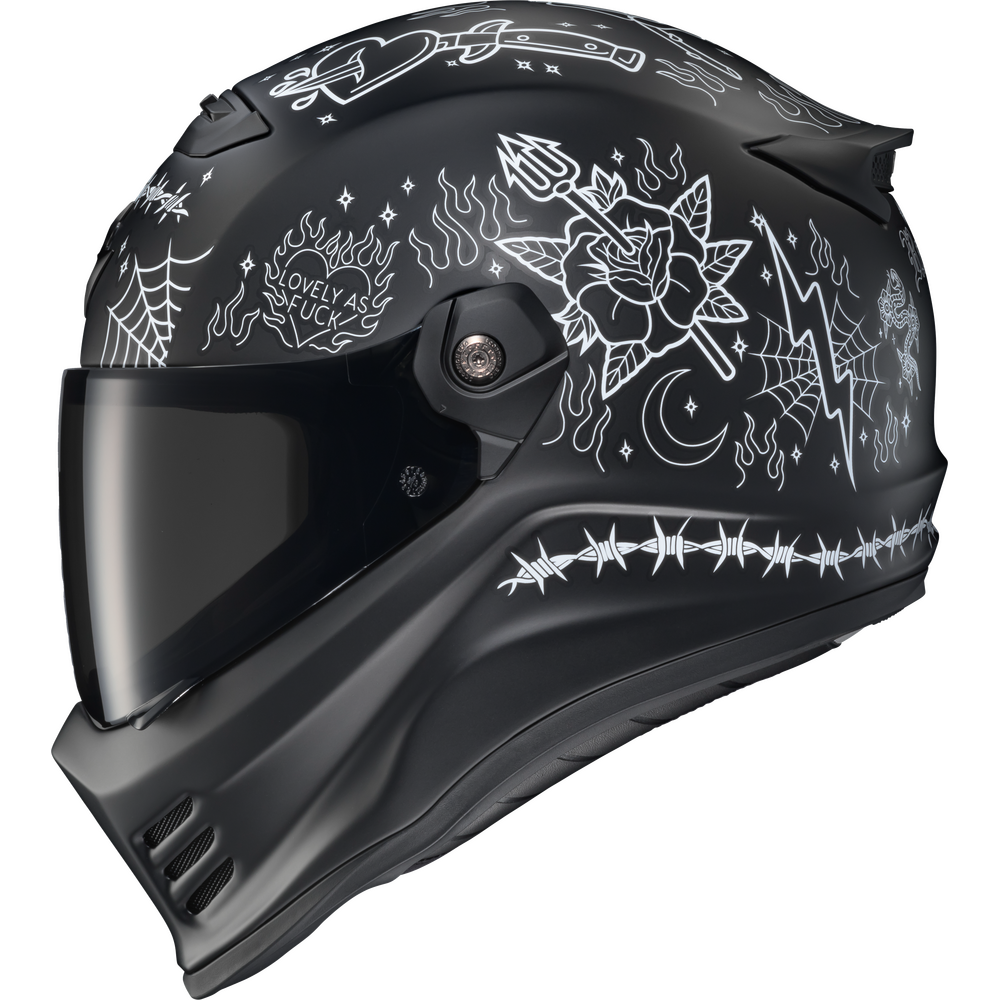A matte black full-face motorcycle helmet with white line-art illustrations of a rose, spiderwebs, a dagger, barbed wire, a crescent moon, and the phrase 'LOVELY AS A FUCK'.