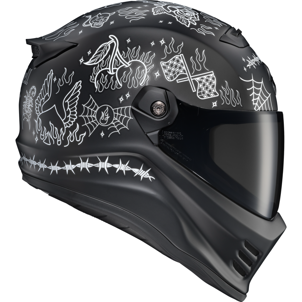 A matte black full-face motorcycle helmet with white line-art illustrations of a bird, flames, spiderwebs, checkered flags, and barbed wire, shown on a plain white background.