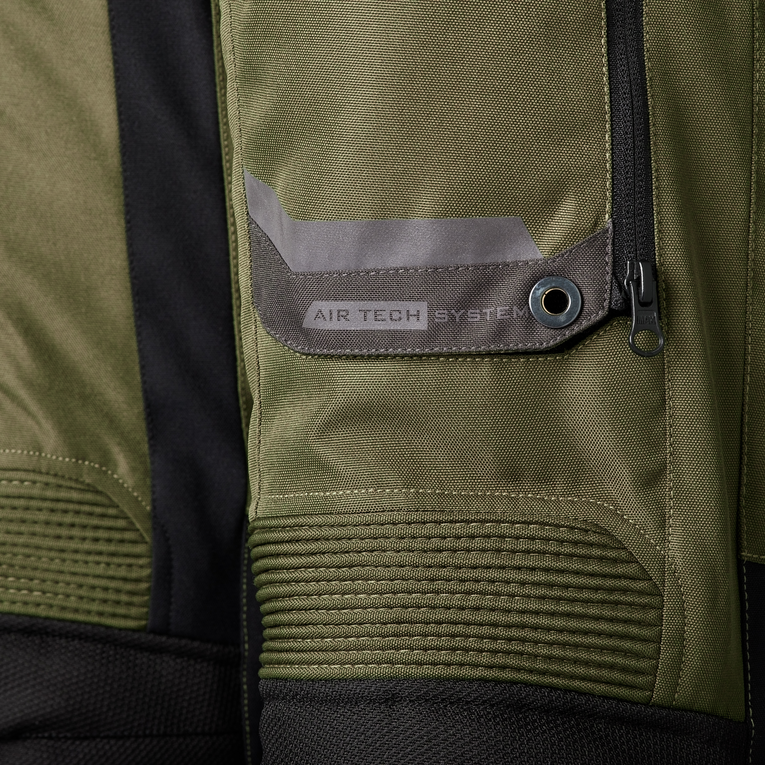 Close-up of an olive green technical jacket with black trim, featuring a zippered pocket with a gray flap and the text 'AIR TECH SYSTEM' printed on it.