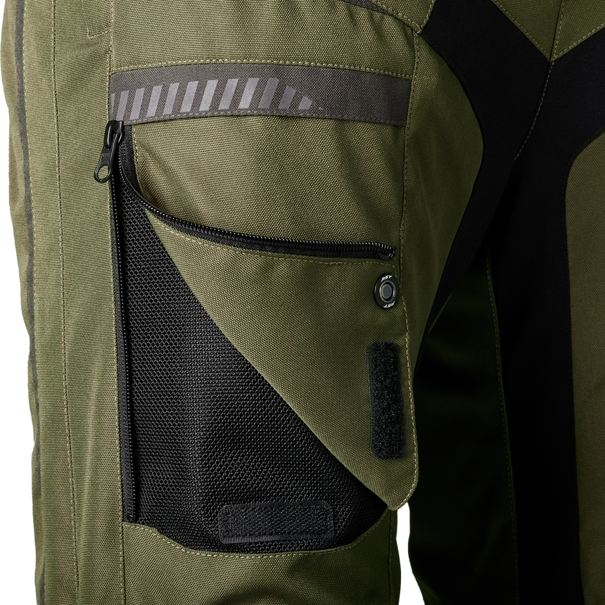 Close-up of olive green and black technical outerwear fabric with a zippered pocket, mesh panel, reflective stripe, and snap detail.