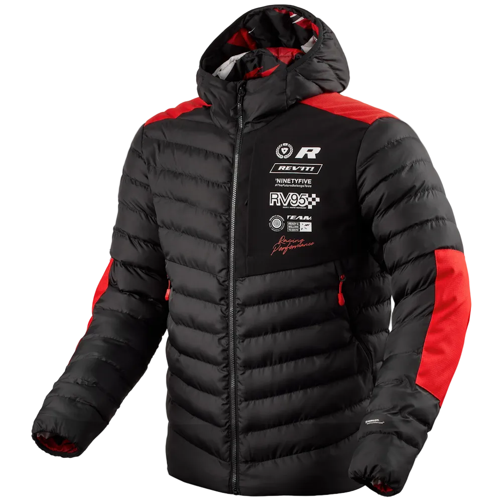 A black puffer jacket with red shoulder and sleeve panels, featuring multiple white and black racing sponsor logos on the left chest, including Rev'it! and Navteq. The jacket is shown on a light gray background.