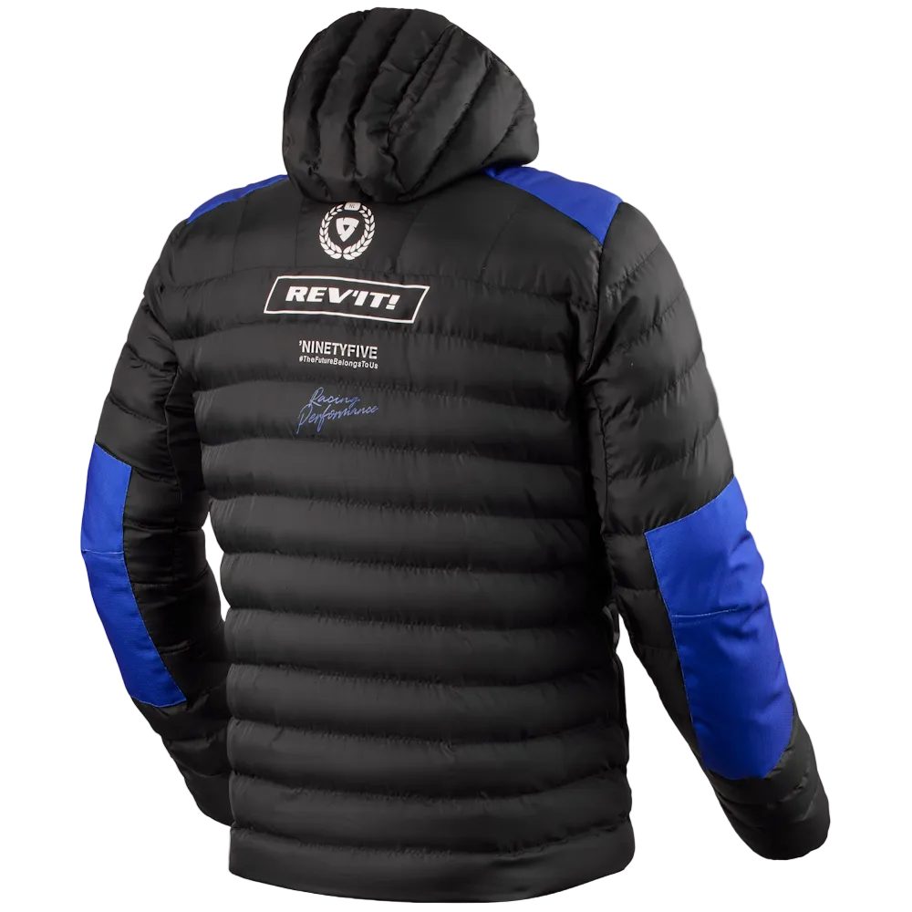 Black puffer jacket with royal blue shoulder and sleeve panels, featuring a hood and multiple sponsor logos on the back, including REV'IT! and NinetyFive, shown against a light gray background.