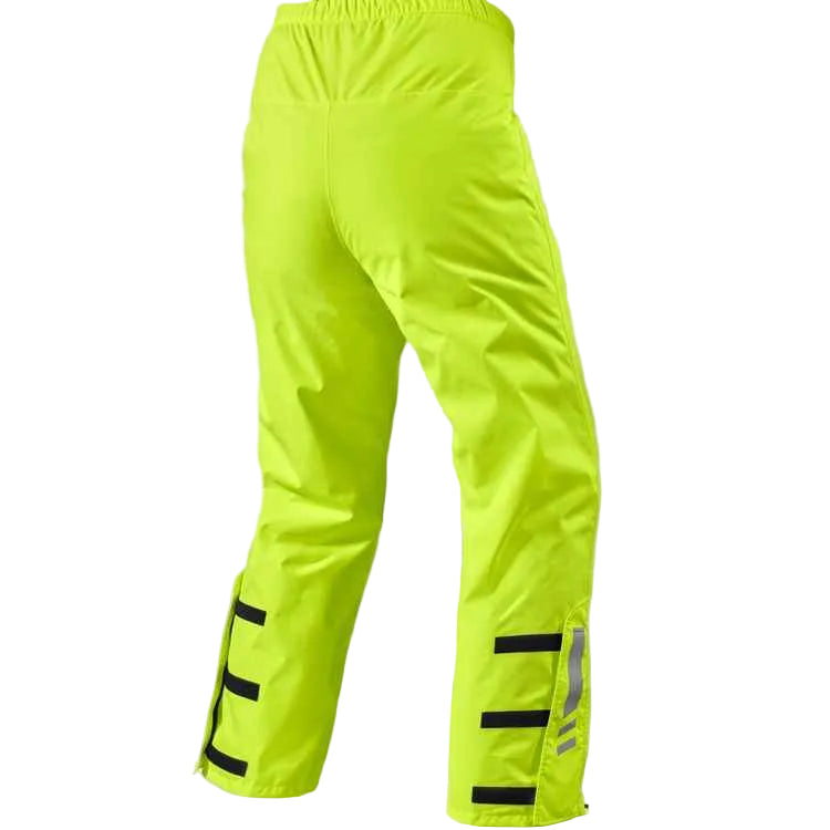 Bright neon yellow-green rain pants with reflective black and silver stripes on the lower legs, shown from the back on a light beige background.