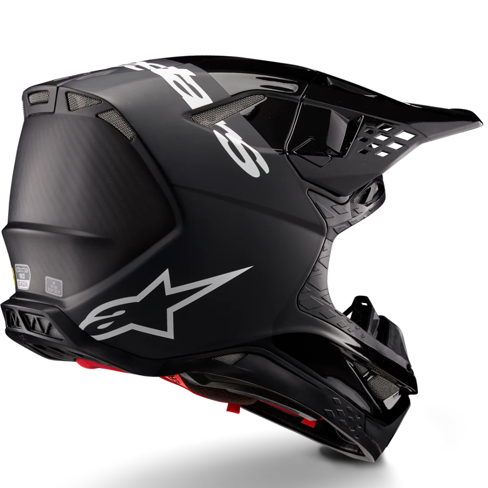 A black Alpinestars full-face motocross helmet with white logo graphics and a small red accent on the chin, shown from a three-quarters angle on a white background.