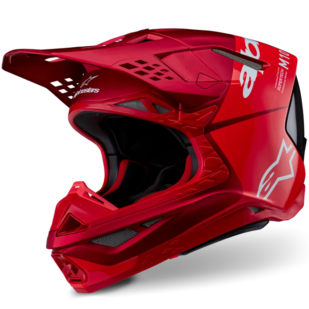 A glossy red full-face motocross helmet with a matching visor, featuring white Alpinestars branding and a black interior, shown on a clean white background.