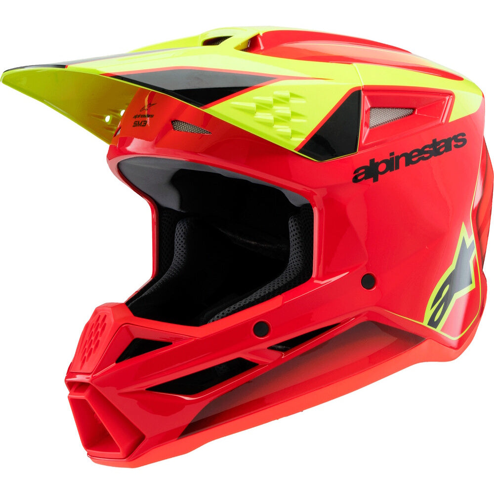 A red and neon yellow Alpinestars full-face motocross helmet with a black visor and interior padding, shown from a three-quarters angle on a white background.